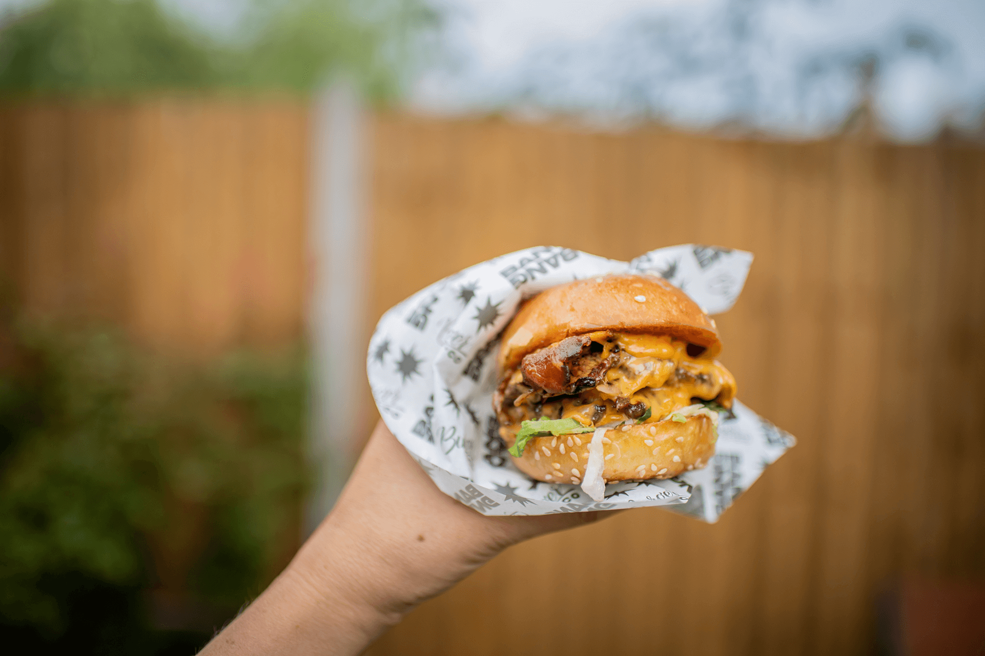 a bang bang bacon slider burger hold and wrapped in a hand